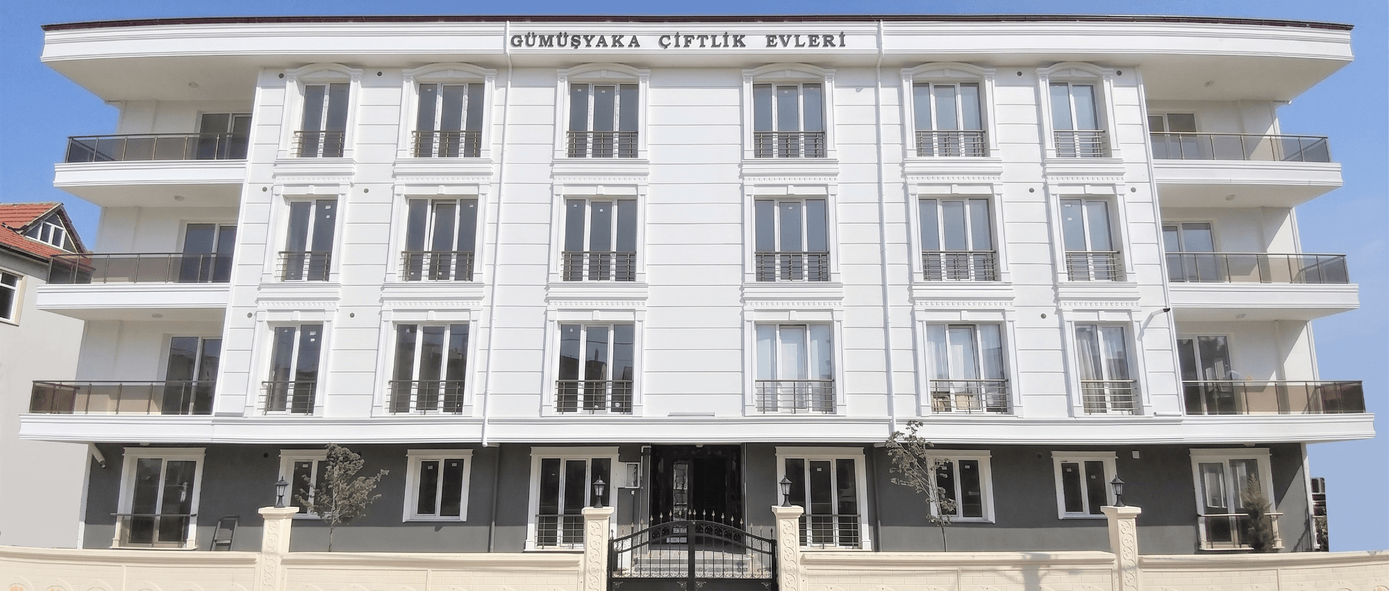 Beyaz cepheli dört katlı apartmanın ön görünümü — Gümüşyaka Konut Projesi II